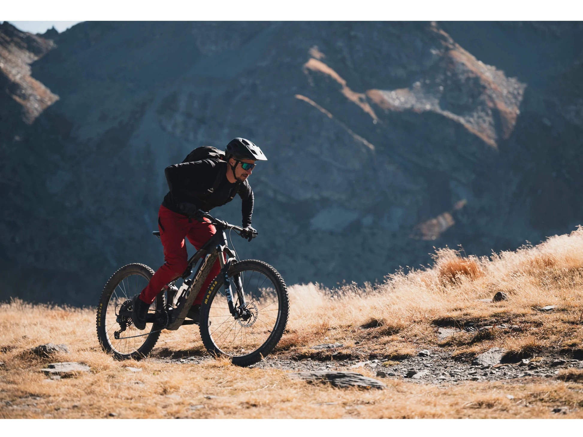 Orbea_Rise_M20_eMTB_full_suspension_man_riding_up_steep_mountain_single_track.webp